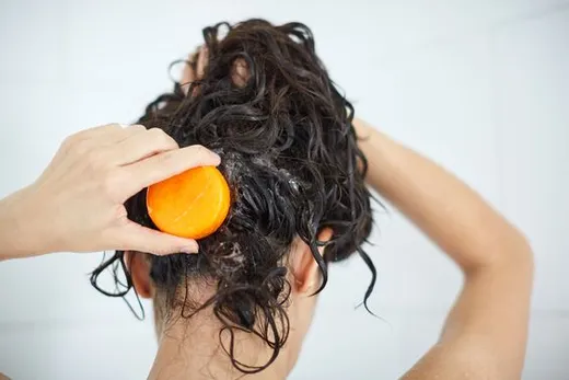 Mujer usando un shampoo sólido.